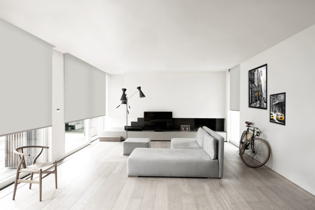 Diaz_rolgordijnen_lichtgrijze rolgordijnen met trendy onderlat_living met grijze zetel en fiets